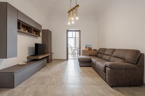 Ein modernes Wohnzimmer mit Flachbildfernseher, braunem Ledersofa, einer eingebauten Regalanlage und einer Pendelleuchte.