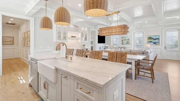 A spacious kitchen with a large island, white cabinetry, and a dining area with a table and chairs. - The Cannon Exchange Building By Charleston Vacays (Charleston)