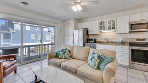 Un apartamento moderno con sala de estar, kitchenette y un balcón con vistas a casas vecinas.