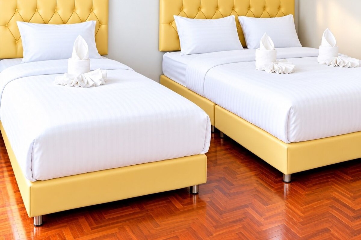 Ein Hotelzimmer mit zwei Betten, jeweils mit gelber Kopfteil und weißer Bettwäsche.