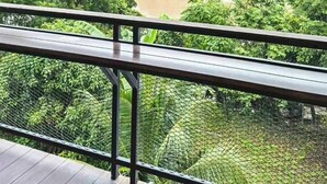 A covered outdoor area with a metal railing, lush greenery, and a river in the background. - The Northern Grace Ping Riverside Hostel (Chiang Mai)