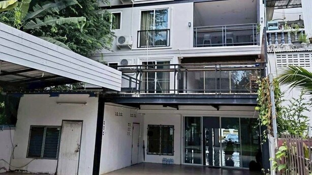 A two-story building with a flat roof, large windows, and a covered outdoor area with a wooden deck. - The Northern Grace Ping Riverside Hostel (Chiang Mai)