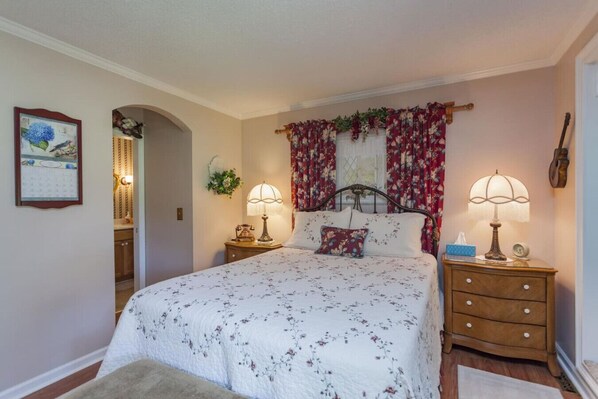 A bedroom with a bed, two bedside tables, a nightstand, a wall-mounted guitar, and a calendar on the wall. - Magnolia Cottage ~ Rockhaven (Mount Juliet)