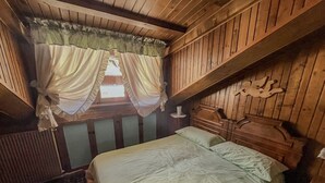 A bedroom with a bed, wooden headboard, curtains, and a window with a view. - Renovated Mountain View Apartment - Auronzo di Cadore (Auronzo di Cadore)