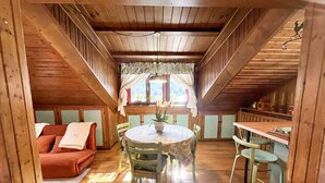 A cozy room with a wooden ceiling, a round table with chairs, a sofa, and a window with curtains. - Renovated Mountain View Apartment - Auronzo di Cadore (Auronzo di Cadore)