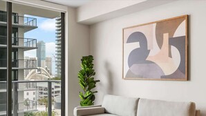 Ein modernes Wohnzimmer mit großem Fenster, einer Couch, einem Couchtisch und einer Pflanze.