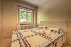 Ein Schlafzimmer mit einem Bett, einem Fenster und einer Heizung.