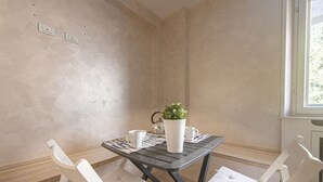 Ein Eckzimmer mit einem Holztisch und weiß gepolsterten Stühlen, einer Topfpflanze und einem Fenster mit Blick.