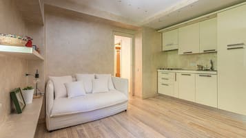 Un interno moderno con un divano, un angolo cottura e un'apertura che conduce in un'altra stanza.