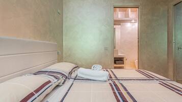 A hotel room with a bed, a bathroom, and a door leading to another room.