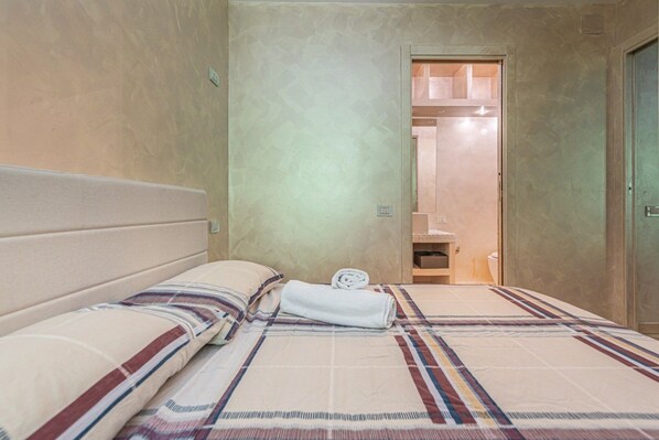 Ein Hotelzimmer mit Bett, Bad und einer Tür zu einem weiteren Raum.