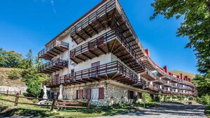 A multi-story building with balconies, a stone facade, and a clear sky. - La Casina - Pian de` Valli (Pian De` Valli)