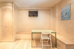 Une pièce avec un bureau, une chaise et une petite fenêtre.