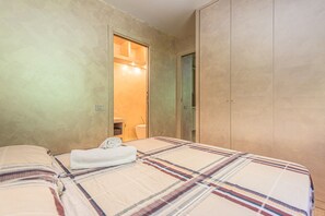 Ein Schlafzimmer mit einem Bett, einer Badezimmertür und einem Kleiderschrank.