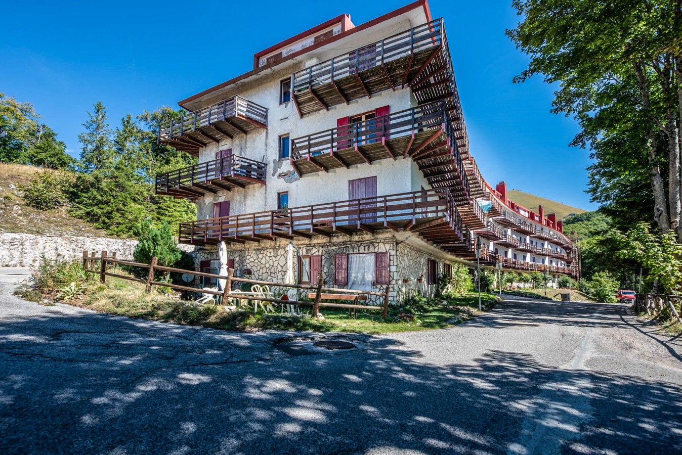 Un edificio de varios pisos con techo a dos aguas, varios balcones y fachada de piedra.