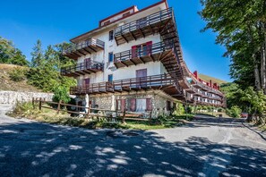 Un immeuble à plusieurs étages, doté d’un toit à forte pente, de nombreux balcons et d’une façade en pierre.