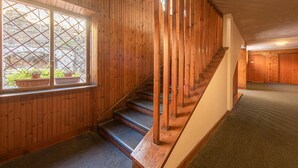 Eine Holztreppe mit Geländer, Teppichboden und einem Fenster mit Blumentöpfen.