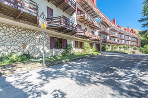 Ein mehrstöckiges Gebäude mit Balkonen, einer Steinfassade und einer Schotterauffahrt.