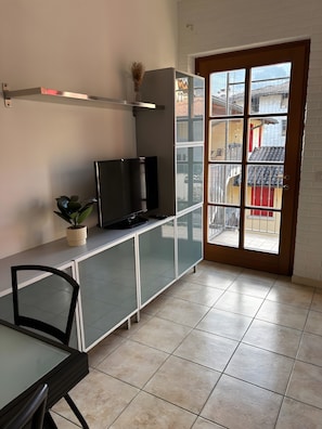 Une cuisine équipée d’un téléviseur, de placards, d’une chaise et d’une plante en pot.