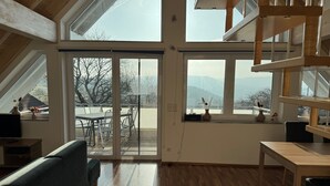 A spacious room with a high ceiling, large windows, and a view of the outdoors. - 5-star maisonette vacation apartment Maria with fantastic Black Forest views (Schramberg)
