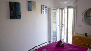 Quarto com cama, penteadeira, espelho e duas pinturas na parede.