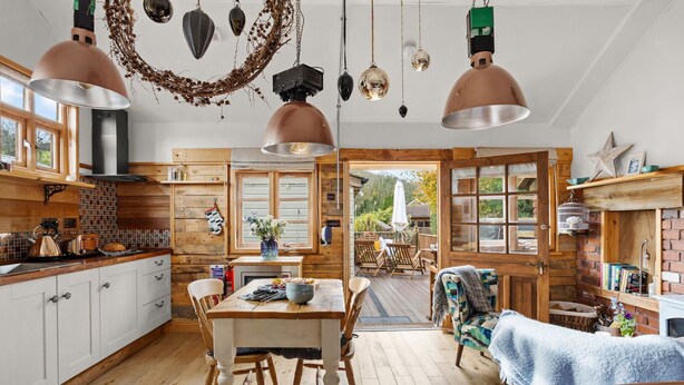 Una cocina acogedora con armarios de madera, una mesa de comedor y lámparas colgantes.