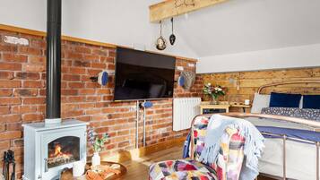 A cozy room with a brick wall, a fireplace, a bed, and a television mounted on the wall.