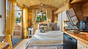 A cozy cabin interior with a bed, a small table with a kettle, and a window with curtains. - Poldhu -  Pet Friendly - Free parking and WiFi (Buryas Bridge)