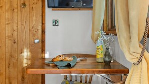 A wooden table with a loaf of bread, a glass vase with flowers, and a bottle of Zephyr Farm cider. - Poldhu -  Pet Friendly - Free parking and WiFi (Buryas Bridge)