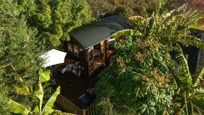 A small, rustic cabin surrounded by dense foliage, featuring a single visible room with a bed and a window. - Poldhu -  Pet Friendly - Free parking and WiFi (Buryas Bridge)