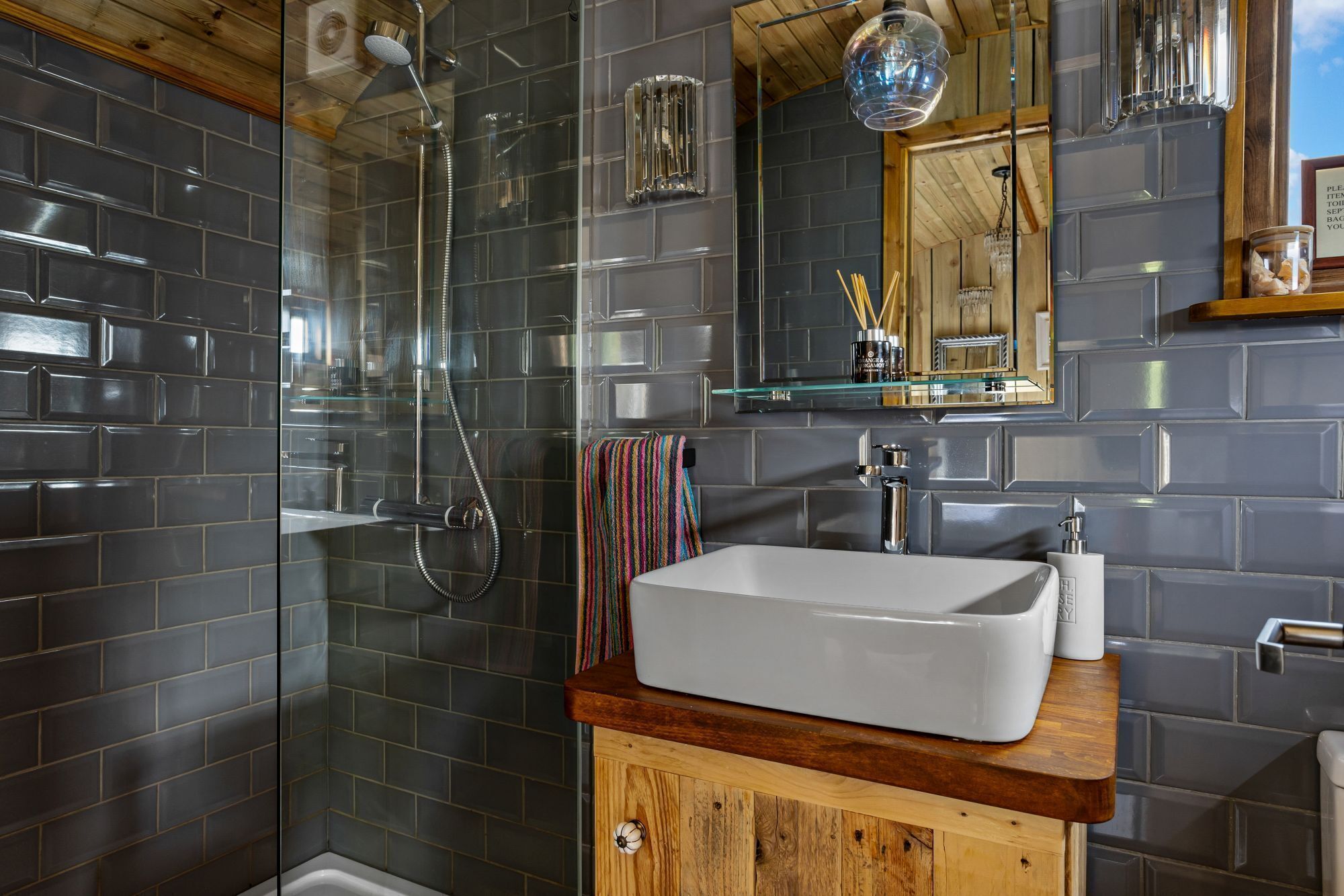 Un baño moderno con ducha de vidrio, lavabo blanco y tocador de madera.