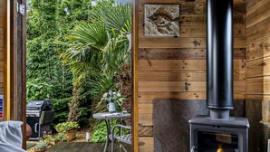 Un espacio al aire libre acogedor, con mesa y sillas, una parrilla y un estufa de leña.