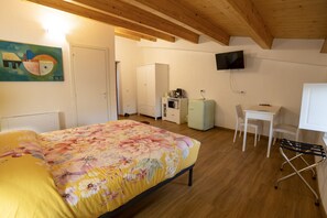 Un dormitorio con cama, escritorio, silla, televisión y armario.