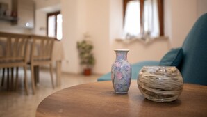A round wooden table with two vases, one with floral patterns and another with a textured design, in a living room with a blue sofa and a dining area in the background. - Casa Arduini - Supino (Supino)