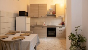 A compact kitchen with a dining area, featuring a refrigerator, stove, sink, and cabinets. - Casa Arduini - Supino (Supino)