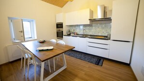 A modern kitchen with white cabinets, a wooden dining table, and a built-in oven. - Casa Anele - Morano Calabro (Morano Calabro)
