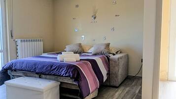 A bedroom with a bed, a bedside table, a chair, and a wall clock.