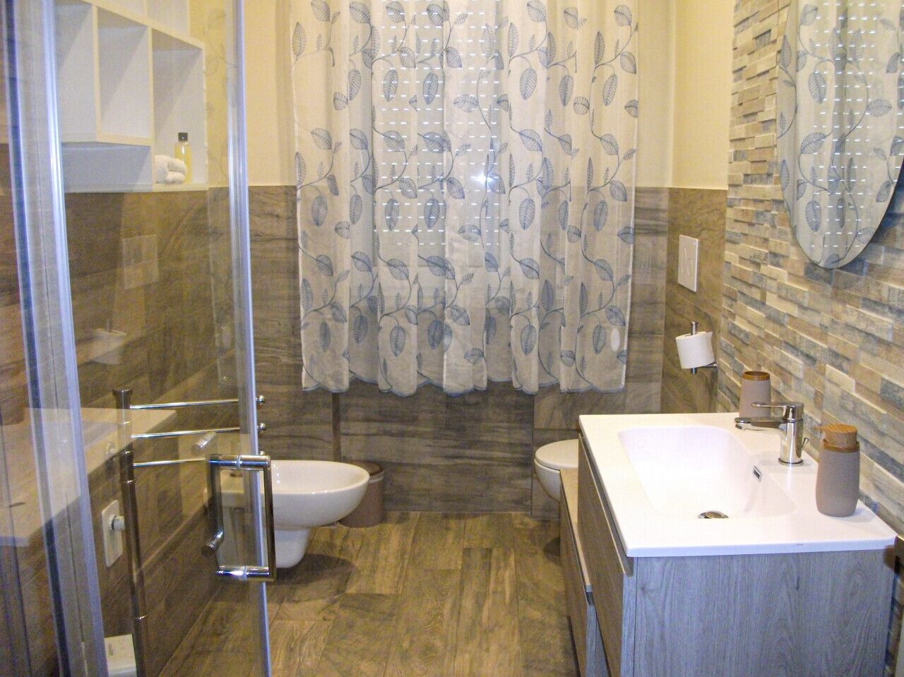 Ein Badezimmer mit Duschkabine aus Glas, einem weißen Waschbecken und einer Toilette.