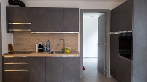 Et moderne køkken med mørke skabe, en rustfri stålvask og en indbygget ovn.