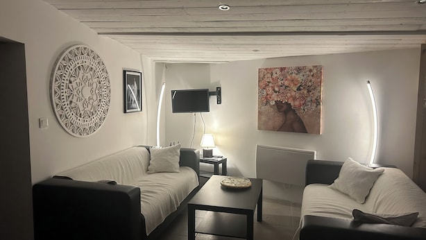Un salon comprenant un canapé, une table basse, un téléviseur à écran plat, une lampe et un tableau accroché au mur.