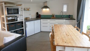 Une cuisine de taille réduite avec des meubles blancs, une table à manger en bois et un four à micro-ondes.