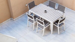 Eine Terrasse mit Tisch, Stühlen und einem Whirlpool, sowie einem gefliesten Boden.