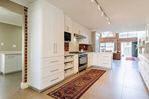 Eine moderne Küche mit weißen Schränken, einem eingebauten Ofen und einem großen Fenster.