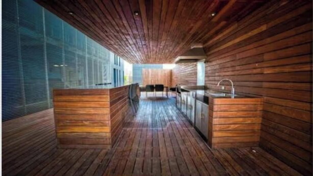 Una cucina moderna con rivestimenti in legno, un'isola centrale e vista sull'esterno attraverso ampie finestre.