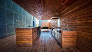 Een moderne keuken met houten lambrisering, een centraal eiland en uitzicht door grote ramen.