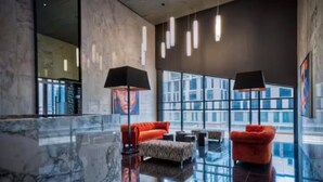 Een moderne lobby met marmeren vloeren, rode banken en zwarte lampen.