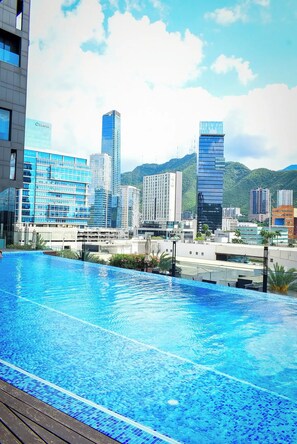 Piscina no terraço com vista para a paisagem urbana, incluindo edifícios modernos e uma montanha ao fundo.