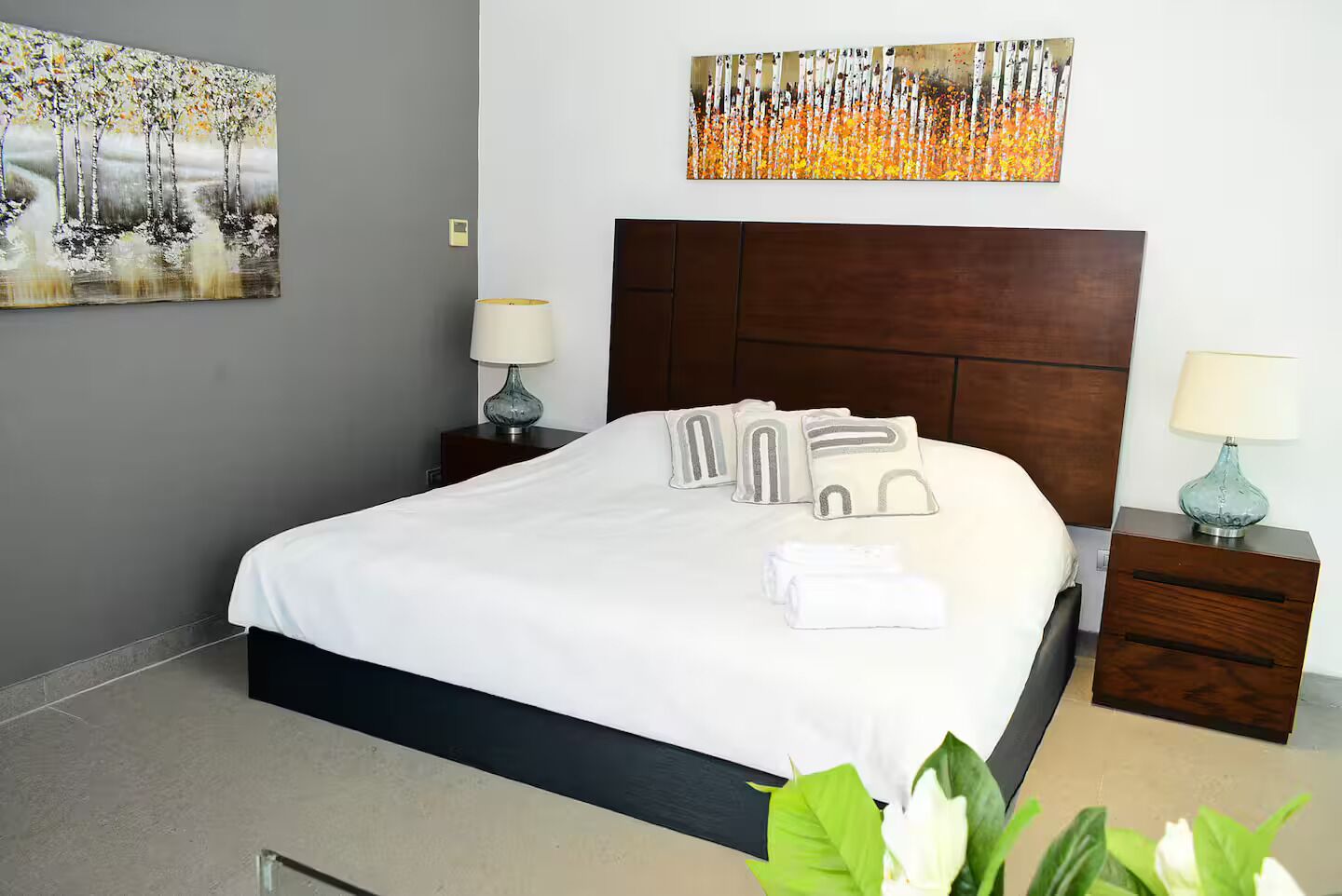 A hotel room with a large bed, two bedside tables with lamps, and artwork on the walls.