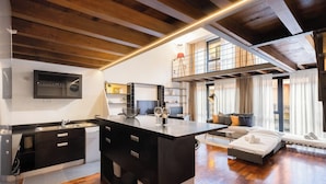 A modern kitchen with a central island, a dining area with a sofa and a small table, and a loft bedroom with a balcony. - Loft Bandiello by BarbarHouse (Milano)