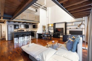Un espace de vie moderne comprenant une cuisine, un coin repas et un espace salon confortable avec un canapé et une table basse.